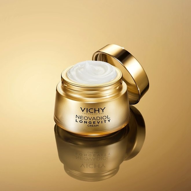 Goldener Cremetiegel: Vichy NEOVADIOL Longevity Cream, geöffnet vor goldenem Hintergrund