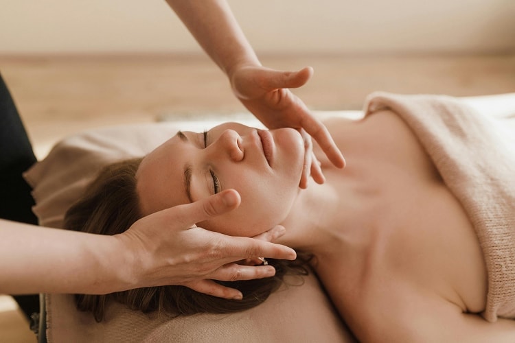 Eine entspannt aussehende Frau bekommt eine Gesichtsmassage.