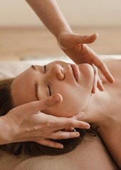 Une femme à l'air détendu se fait faire un massage du visage.