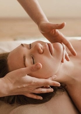 Une femme à l'air détendu se fait faire un massage du visage.