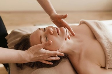 Une femme à l'air détendu se fait faire un massage du visage.
