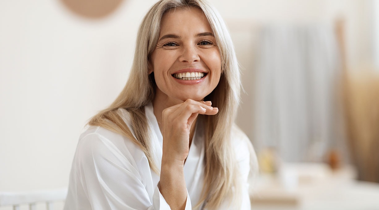 Lächelnde Frau im Bademantel zeigt Zufriedenheit nach Hautpflege