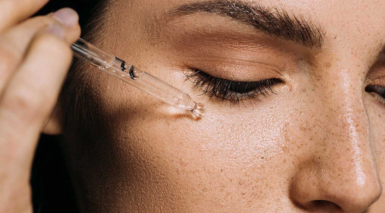 Detailaufnahme einer Gesichtspartie beim Auftragen eines Serums zur Minderung von Pigmentflecken