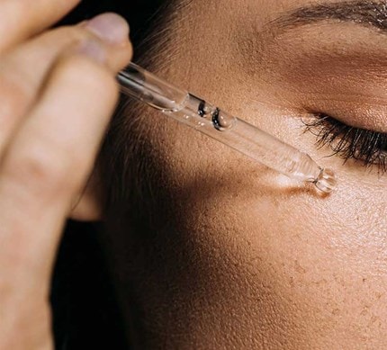 Detailaufnahme einer Gesichtspartie beim Auftragen eines Serums zur Minderung von Pigmentflecken