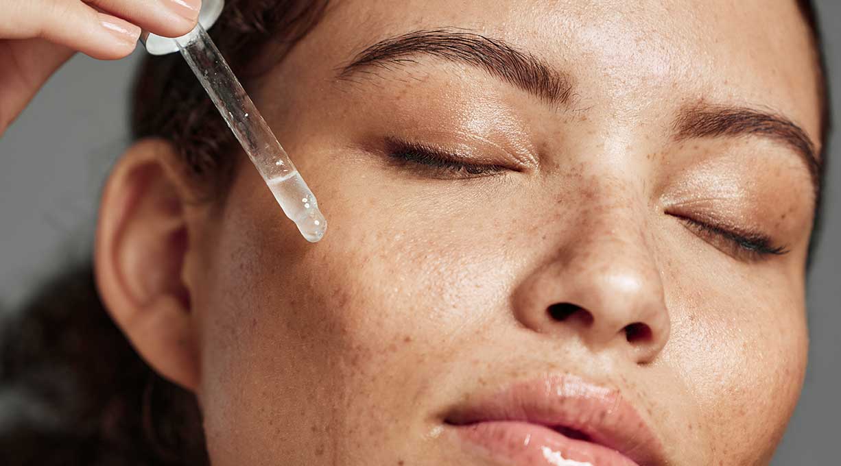 Nahaufnahme zeigt Anwendung eines flüssigen Serums auf der Wange