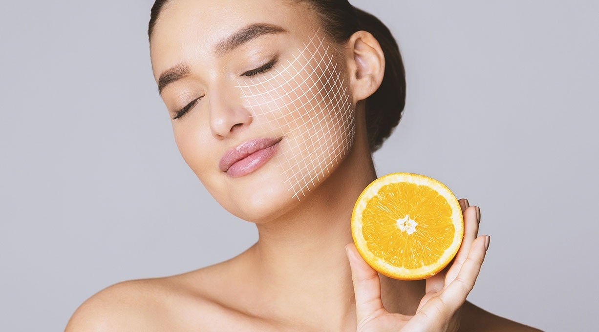 Frau mit geschlossenen Augen genießt frische Zitrusnote, Orange als Vitamin-C-Quelle.