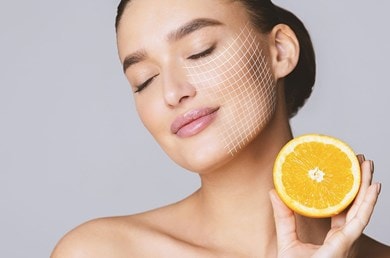Frau mit geschlossenen Augen genießt frische Zitrusnote, Orange als Vitamin-C-Quelle.