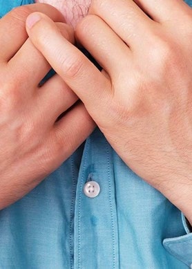 Un homme à la chemise trempée de sueur au niveau du torse tient son col à deux mains.