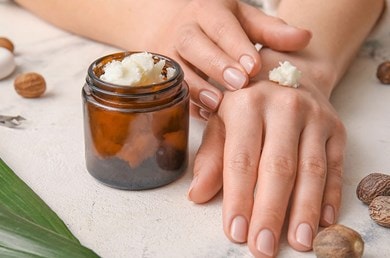 Nahaufnahme von Händen, die Pflegecreme mit Sheabutter auftragen – natürliche Feuchtigkeitspflege für trockene Haut
