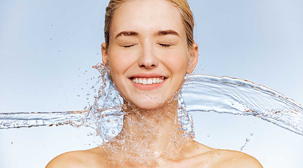 Wasser umspült lachendes Gesicht – Symbol für Frische, Vitalität und langanhaltende Feuchtigkeitspflege