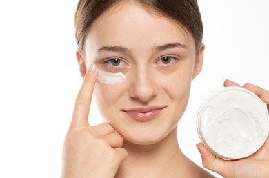 Frau pflegt Augenpartie mit Creme, sorgt für Frische und hydratisierte Haut