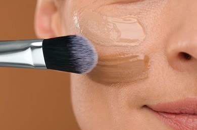 Pinsel verteilt flüssige Foundation auf Haut, sorgt für einen frischen, gleichmässigen Teint
