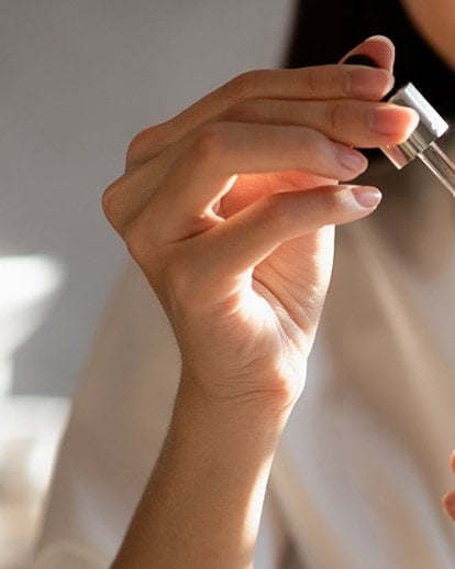 Frau hält die Pipette eines geöffneten Serums in der Hand