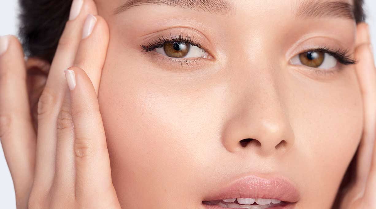 Frau mit braunen Augen hält ihre Hände an die Schläfen