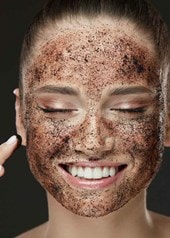 Gesicht einer jungen Frau das mit einem braunen Peeling bedeckt ist