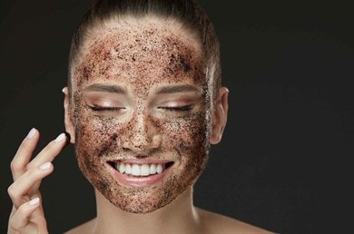 Gesicht einer jungen Frau das mit einem braunen Peeling bedeckt ist