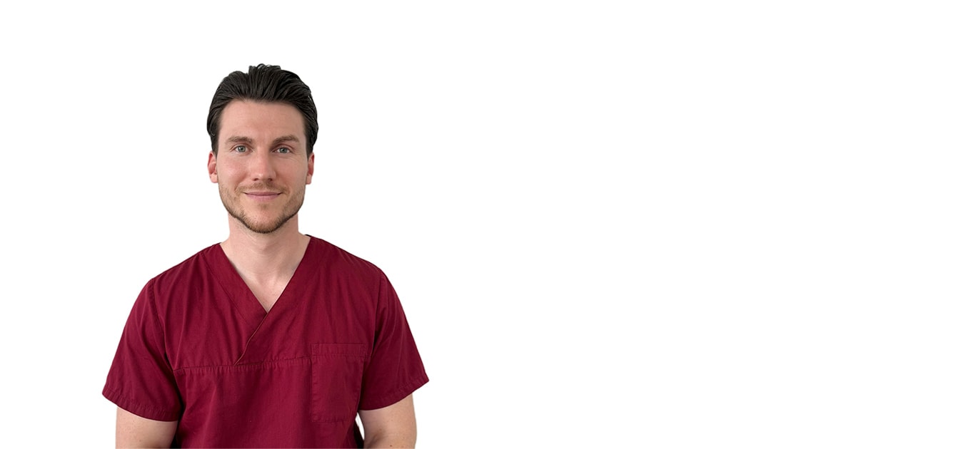 Dr. Rouben Czwikla im dunkelroten Arztkittel schaut frontal in die Kamera