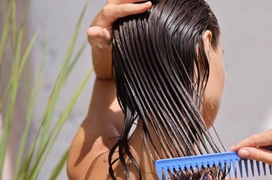 Frau mit braunen Haaren kämmt ihre nassen Haare mit einem grobzinkigen Kamm