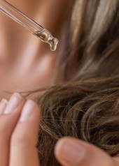 Pipette gibt Rizinusöl auf trockene Haarspitzen zur Pflege