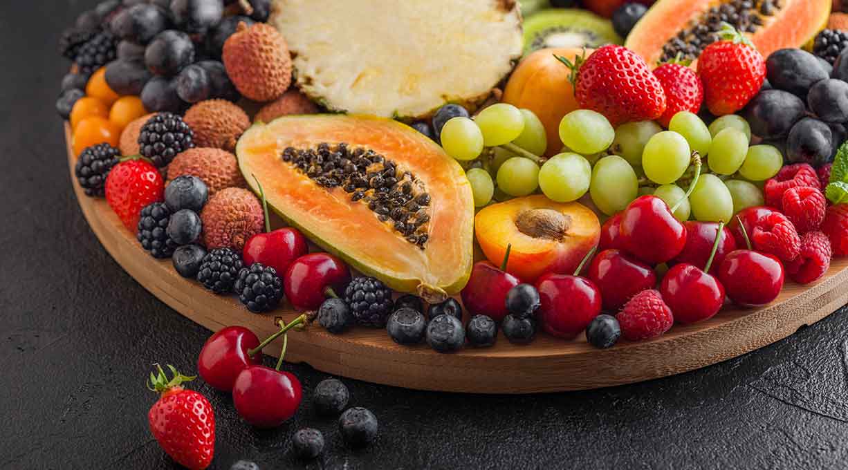 Ein Teller voll mit Obst wie Beerenfrüchte, Kirschen, Trauben, Papaya und Ananas