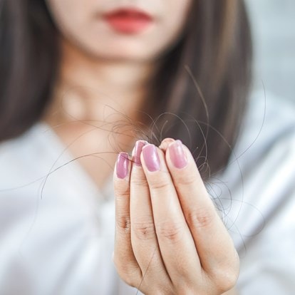 Frau hält einen Büschel Haare zwischen den Fingern