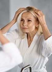 Une femme d'âge moyen regarde sa raie devant le miroir