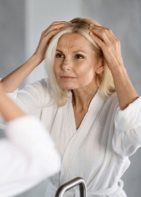 Une femme d'âge moyen regarde sa raie devant le miroir