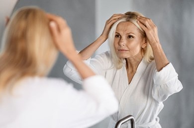 Une femme d'âge moyen regarde sa raie devant le miroir