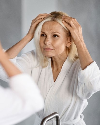 Une femme d'âge moyen regarde sa raie devant le miroir