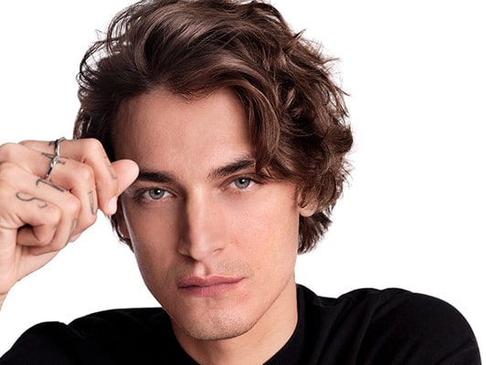 Nahaufnahme eines dunkelhaarigen,männlichen Models mit mittelkurzen Haaren, das sich in die Haare greift