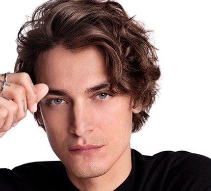 Nahaufnahme eines dunkelhaarigen,männlichen Models mit mittelkurzen Haaren, das sich in die Haare greift
