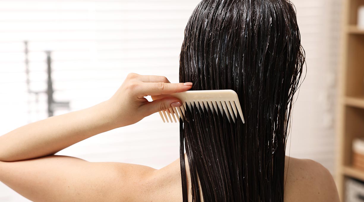 Femme brune de dos, se peignant les cheveux avec un peigne