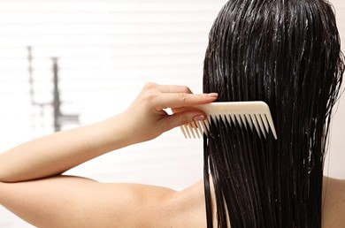 Femme brune de dos, se peignant les cheveux avec un peigne