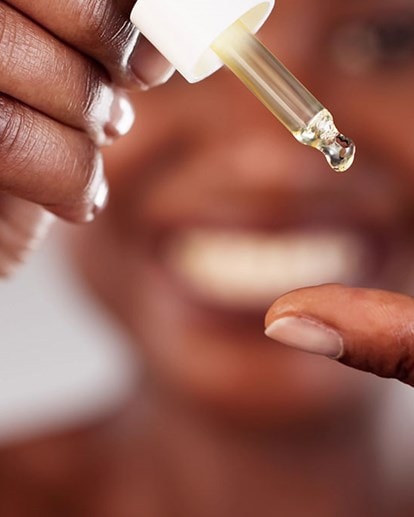 Nahaufnahme einer Hand, die eine Serum-Pipette hält.