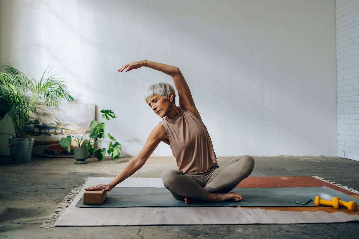 Ältere Frau macht Yoga und Dehnübungen für Beweglichkeit und Gelenke 