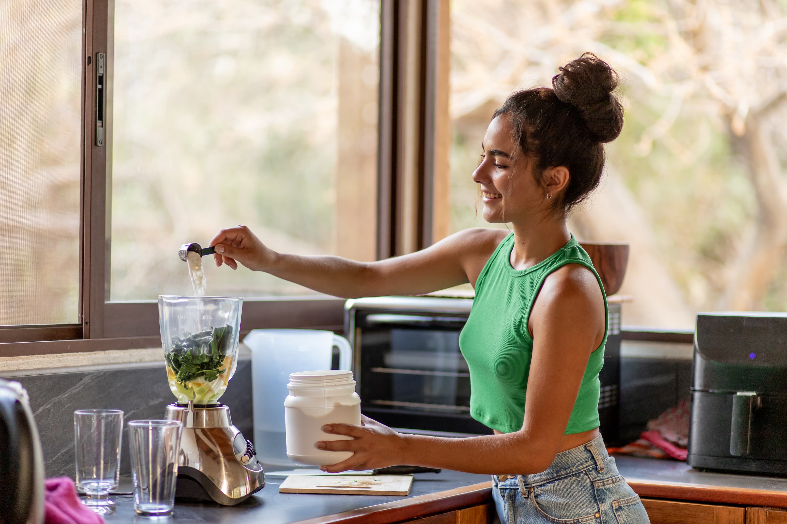 Frau bereitet frischen Smoothie in der Küche vor 
