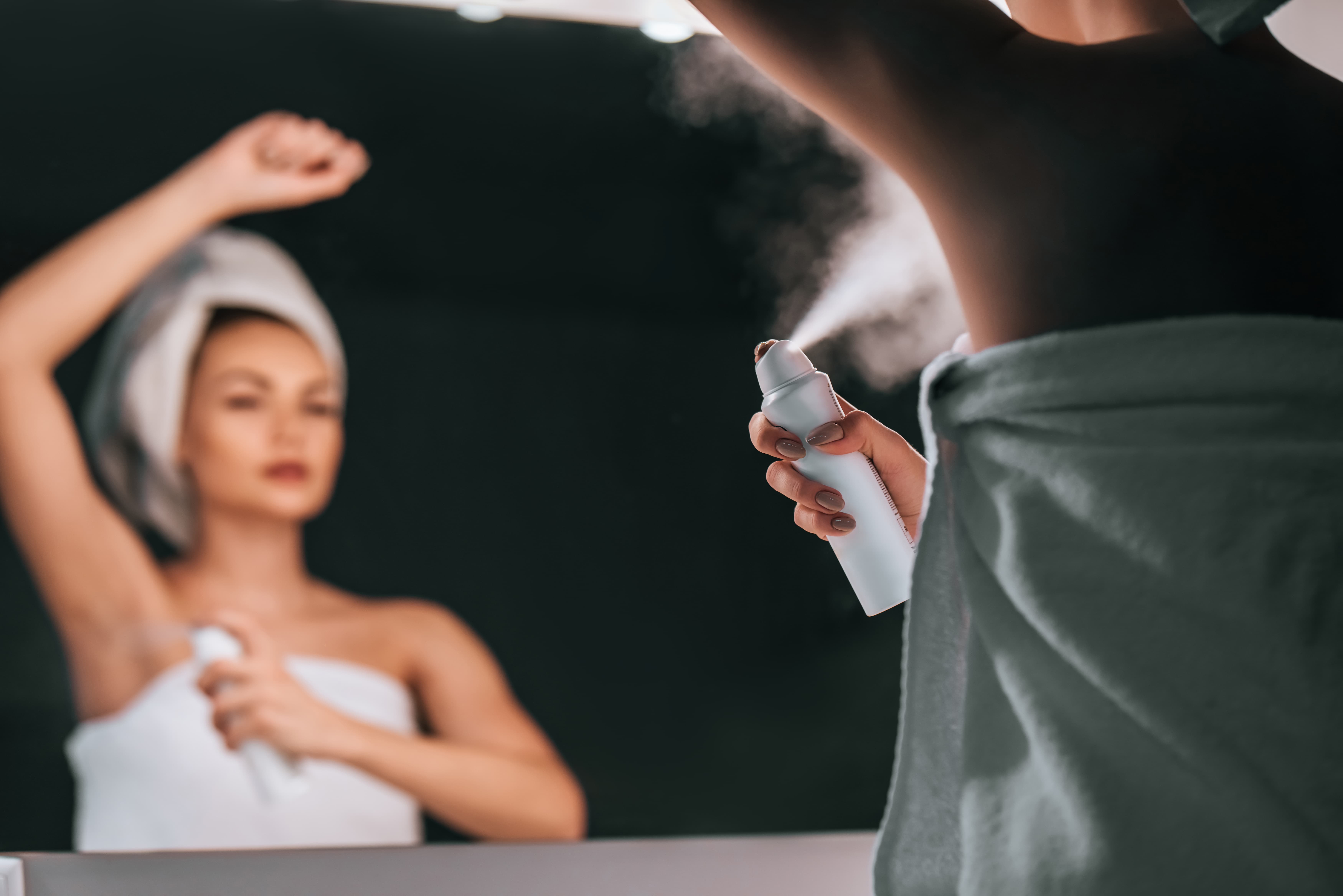 Frau sprüht nach dem Duschen Deodorant unter die Achsel