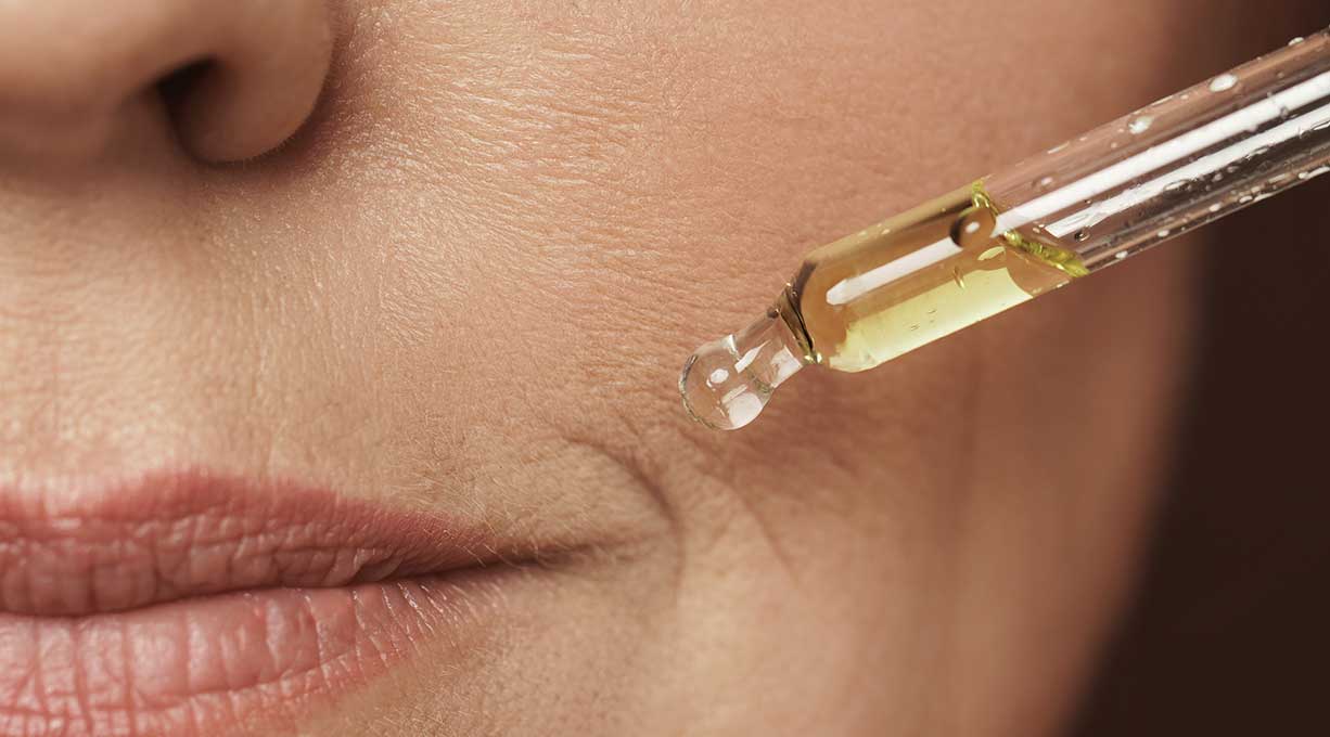 Nahaufnahme einer weiblichen Mundpartie und einer Pipette gefüllt mit Serum.