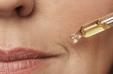 Nahaufnahme einer weiblichen Mundpartie und einer Pipette gefüllt mit Serum.
