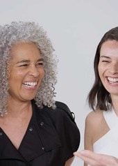 Vier Frauen lachen und lächeln fröhlich miteinander.