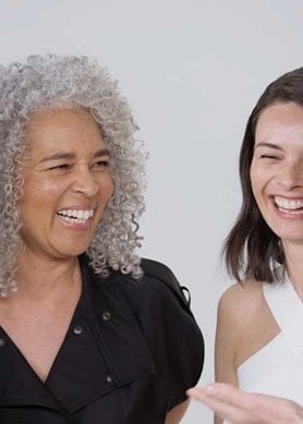 Vier Frauen lachen und lächeln fröhlich miteinander.
