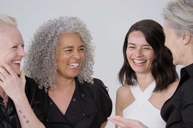 Vier Frauen lachen und lächeln fröhlich miteinander.
