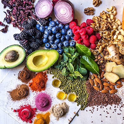 Obst, Gemüse, Nüssen und Gewürzen als gesunde Lebensmittel-Auswahl auf einer Holzplatte