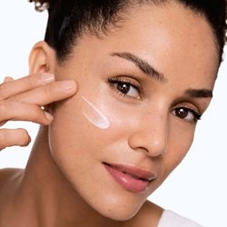 Application de la protection solaire Vichy sur le visage d'une jeune femme.