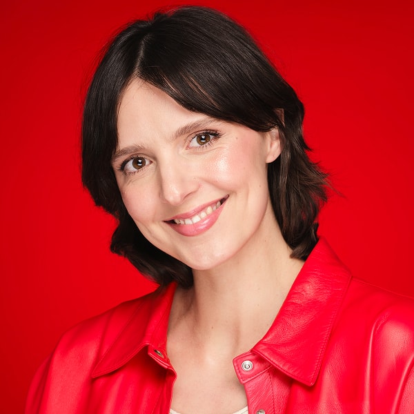 Portrait d’un mannequin à la peau brune portant une blouse rouge et au teint soigné
