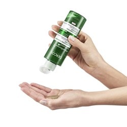 Une main droite tient le DERCOS Shampoing antipelliculaire K à l'envers.