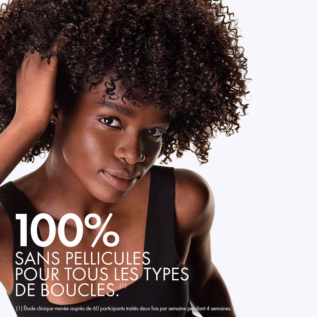 Femme à la peau foncée avec cheveux afro mi-longs, cuir chevelu sain et sans pellicules après quatre semaines d’usage de Vichy Dercos.