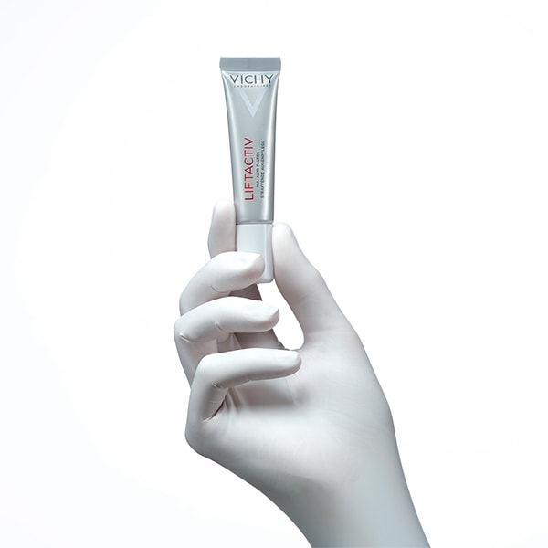 Hand mit weissem Handschuh hält die LIFTACTIV Augenpflege von Vichy mit Daumen und Zeigefinger