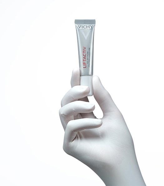 Hand mit weissem Handschuh hält die LIFTACTIV Augenpflege von Vichy mit Daumen und Zeigefinger