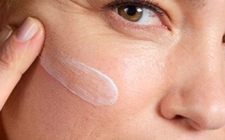 Application d'une crème pour visage sur la joue droite d'une femme.